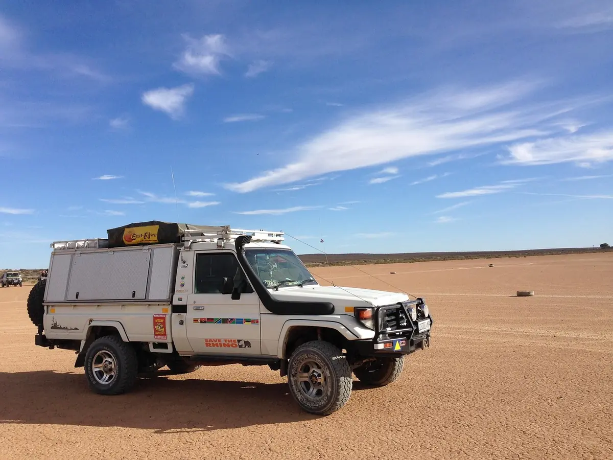 Equipped four-wheel-drive pickup with a roof rack, snorkel and bull bar parked on open desert ground