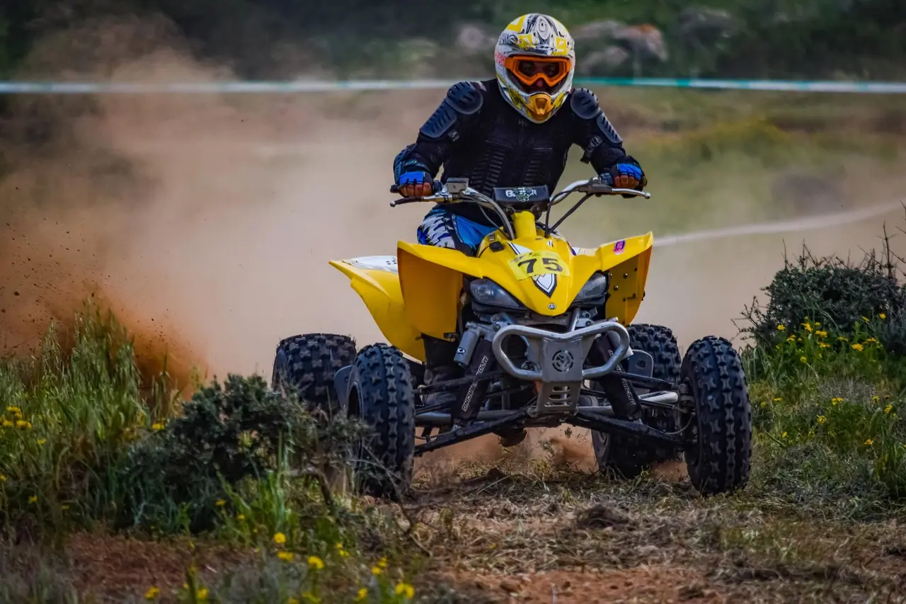 Front view of a quad with its two knobby front tires on a dirt track