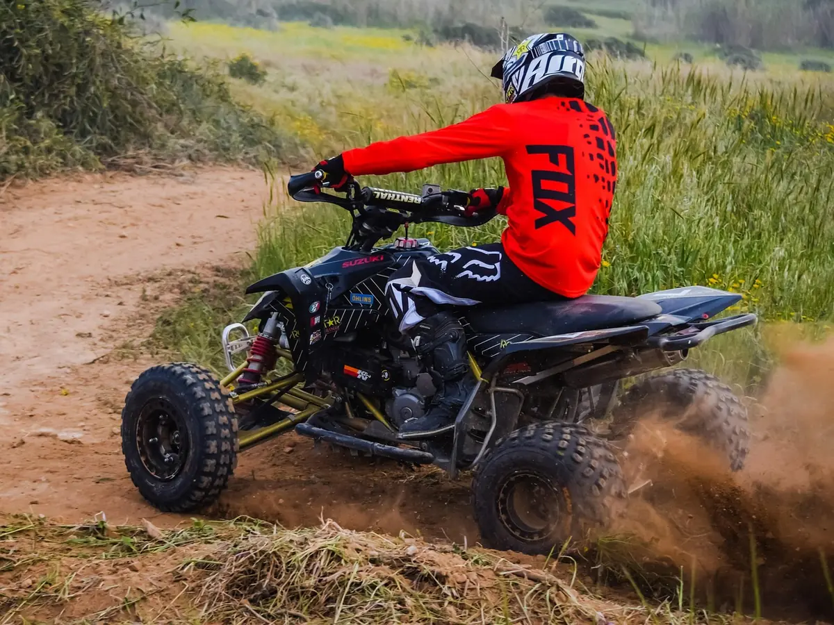 Side view of a quad with knobby tires leaning through a dirt corner