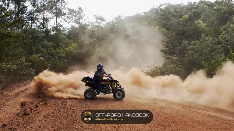 ATV rider sliding through a dust cloud on a dirt trail — Off-Road Handbook