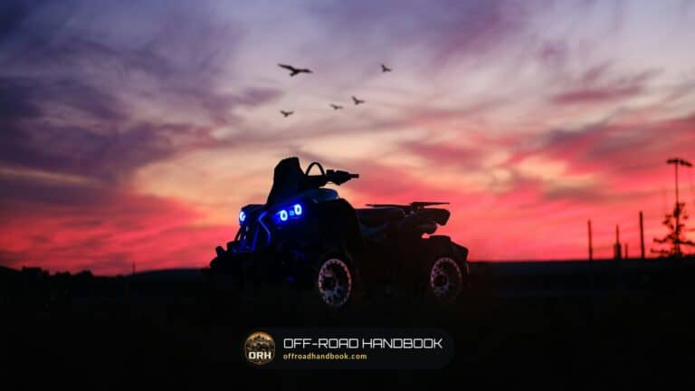 ATV rider silhouetted against a red and purple sunset sky