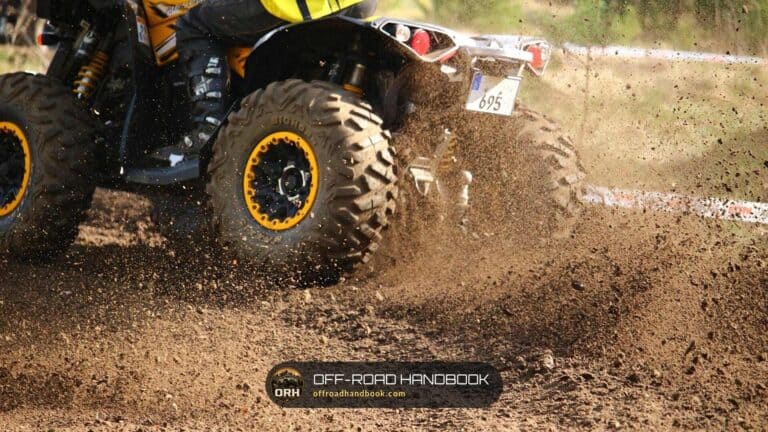 Rear knobby tire of a quad throwing dirt on a motocross-style track