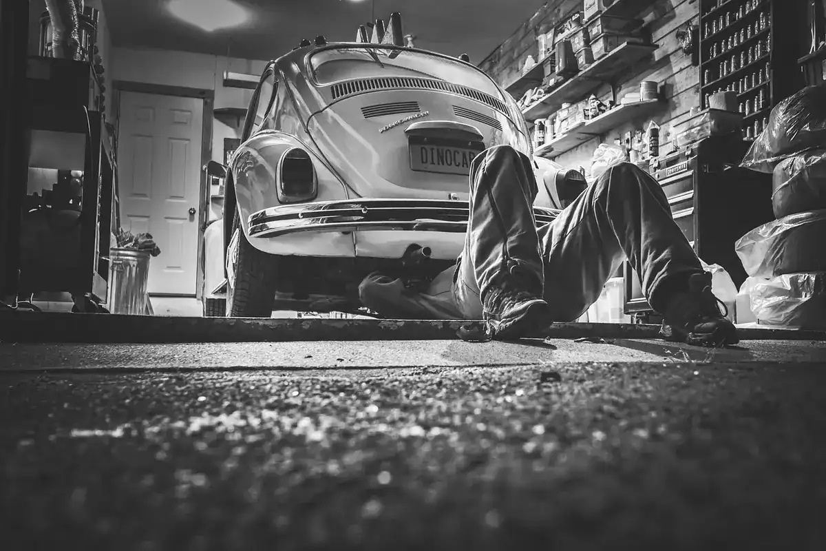 Mechanic lying under a car in a home garage, black and white photo