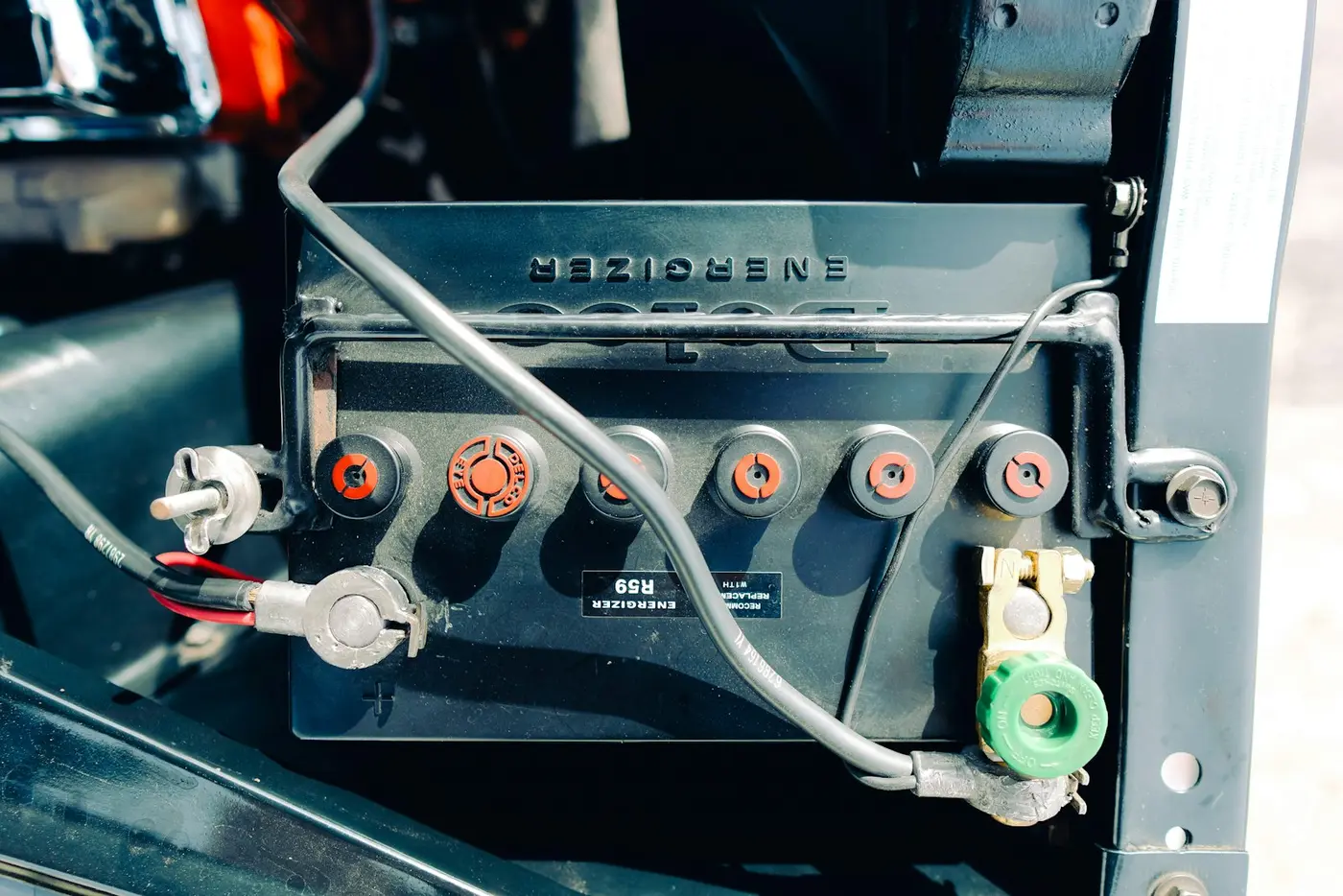 Vehicle battery with cable clamps connected under the hood
