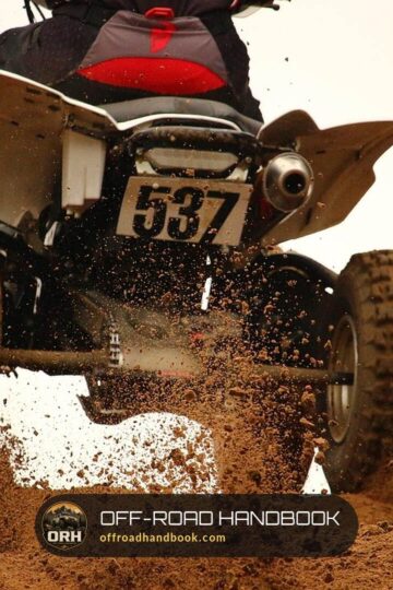 Rear view of a sport quad ATV throwing dirt as it leaves a dirt berm