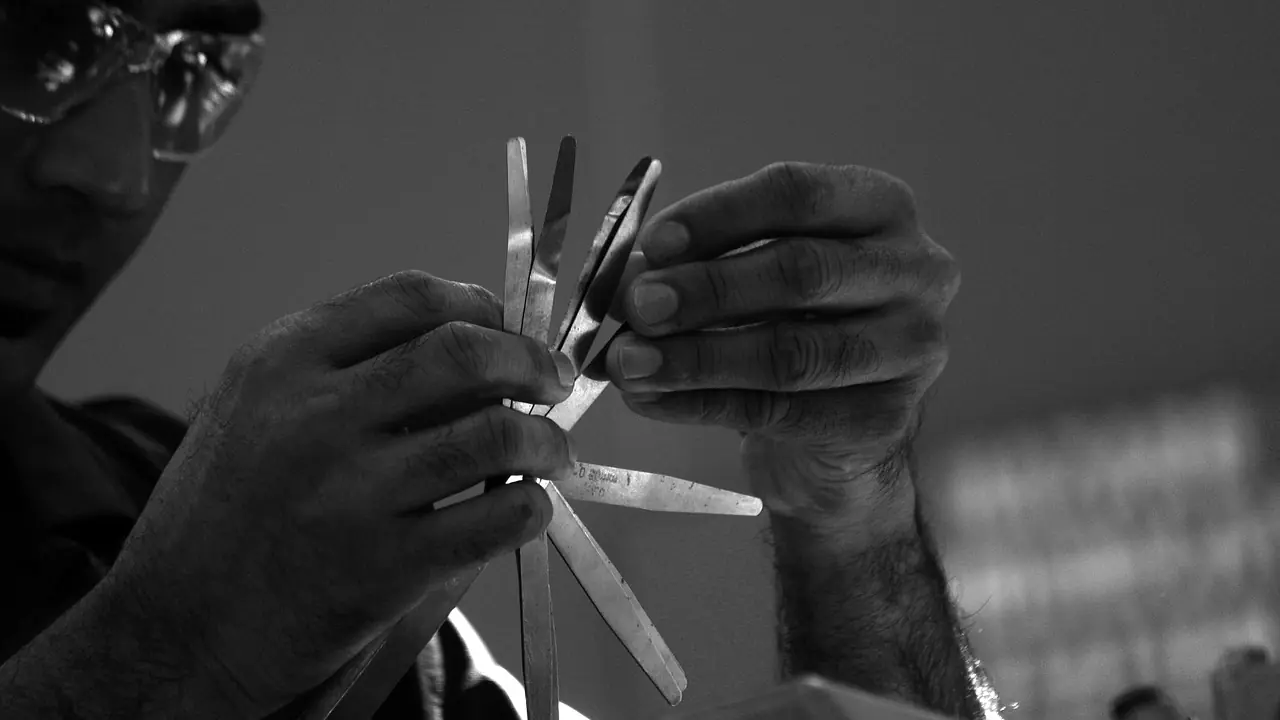 Mechanic's hands fanning out a set of feeler gauge blades, the tool used to measure valve clearance
