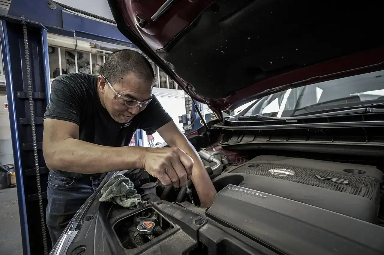 Mechanic leaning into an engine bay to check fluid levels and components