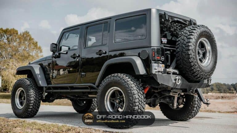 Black lifted Jeep Wrangler Unlimited with large off-road tires parked on pavement