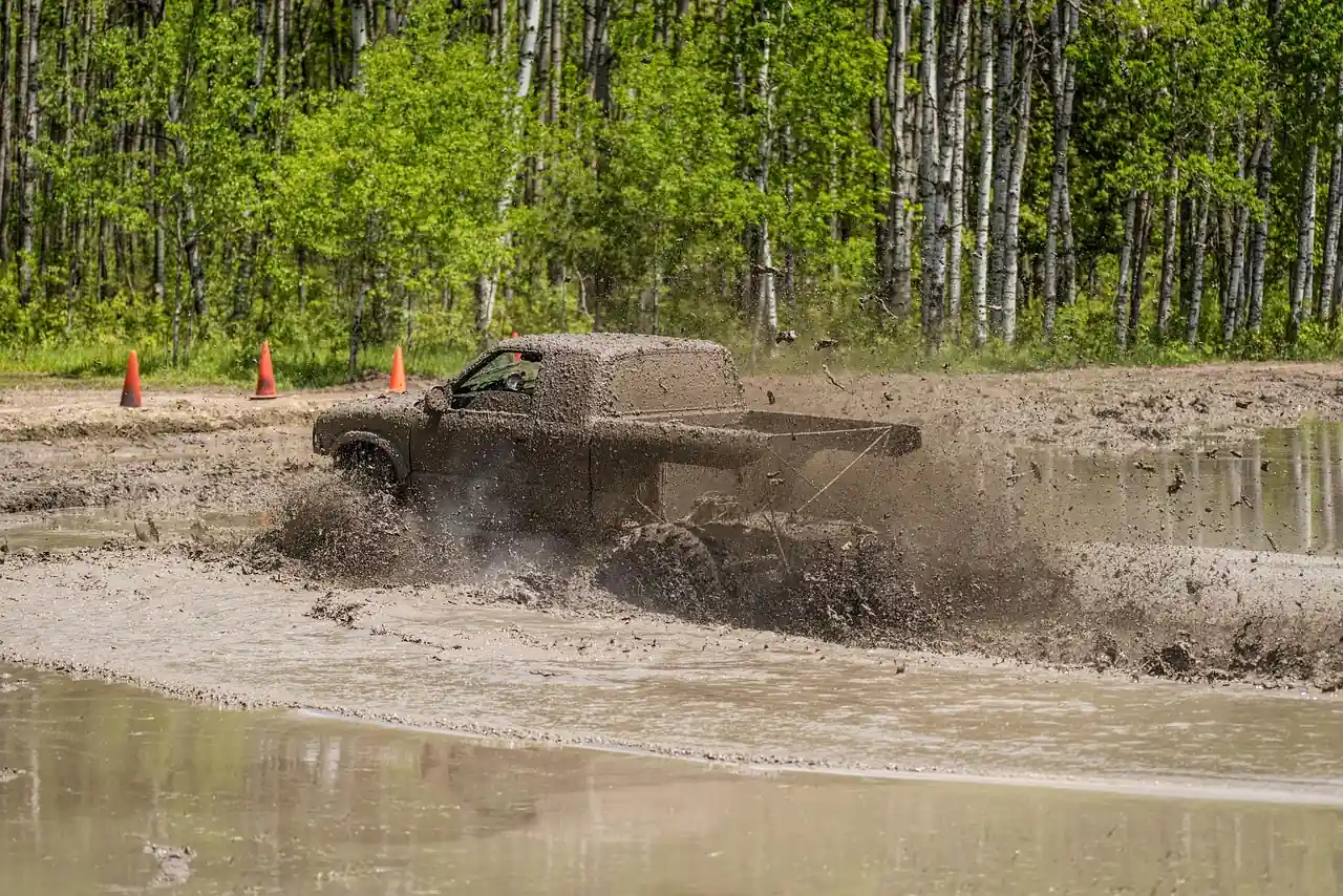 Pickup truck driving through a muddy water pit at a mud park