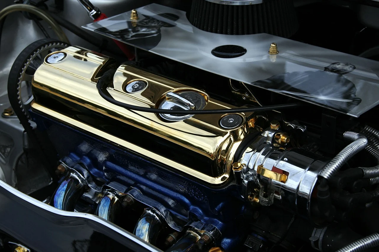 Close-up of a customized engine with a gold-colored valve cover and blue plug wires