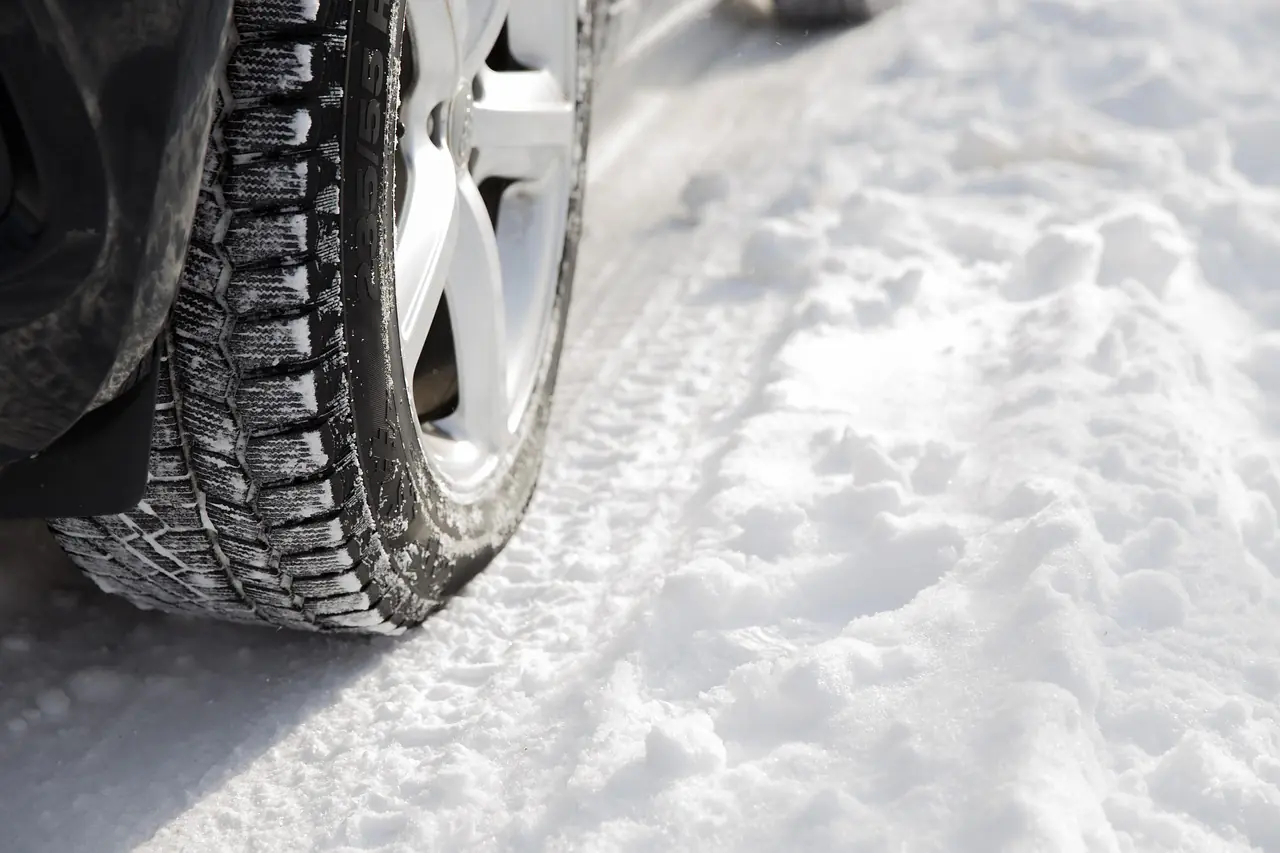 Close-up of a tire tread pressed into packed snow beside the wheel