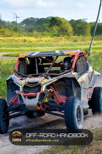 Can-Am sport side-by-side kicking up dust on a dirt trail beside a marsh