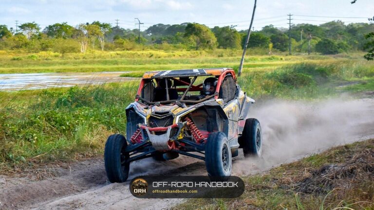 Can-Am sport side-by-side kicking up dust on a dirt trail beside a marsh