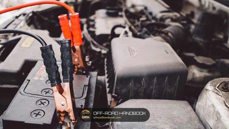 Jumper cables clamped to a car battery under the hood — Off-Road Handbook
