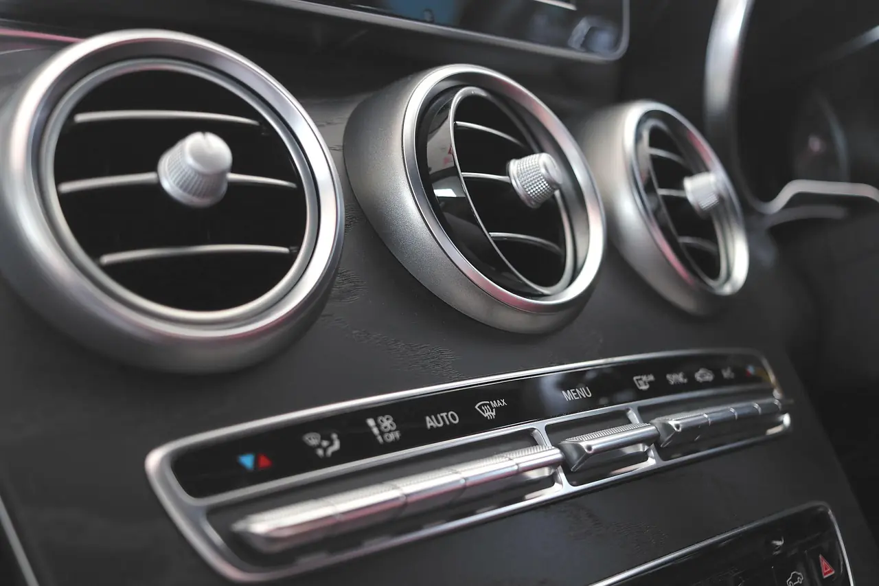 Climate control buttons and three round air vents on a car dashboard (not a Jeep)
