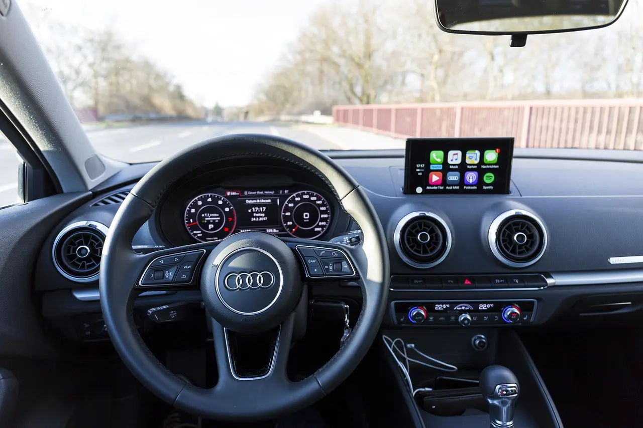 Car interior with a touchscreen showing phone app icons above the center vents, in an Audi rather than a Jeep