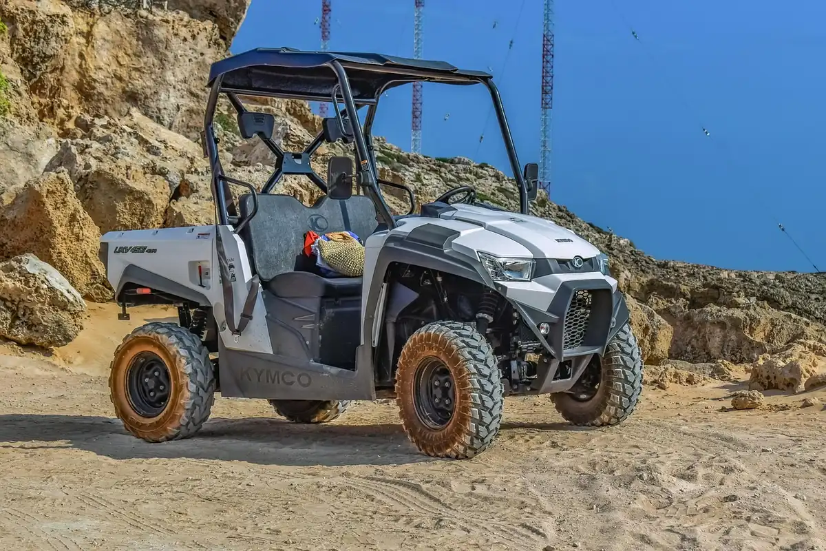 White and gray side-by-side with mud-stained tires parked on a sandy trail