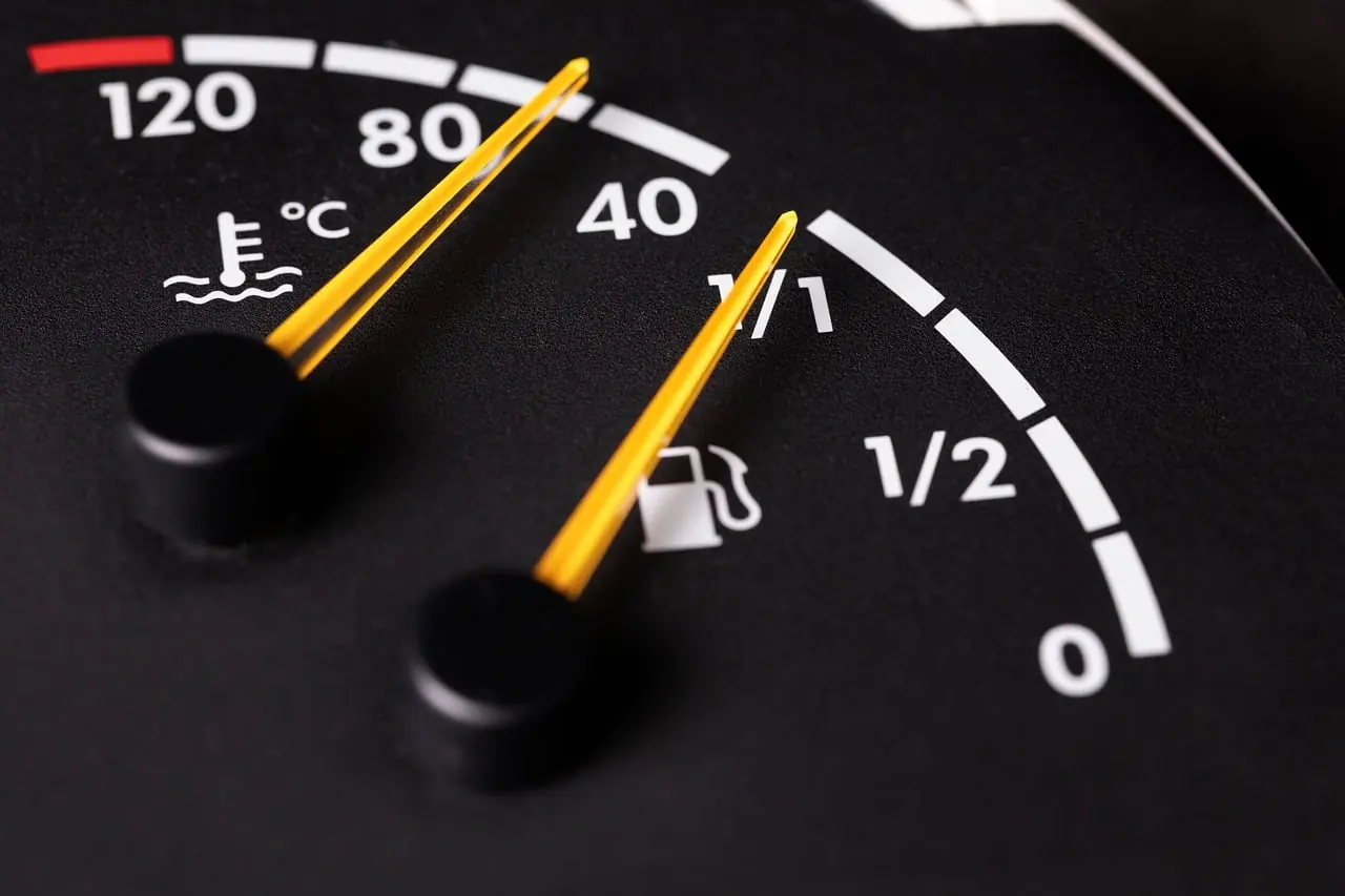 Close-up of a car instrument cluster showing a coolant temperature gauge with a yellow needle next to the fuel gauge