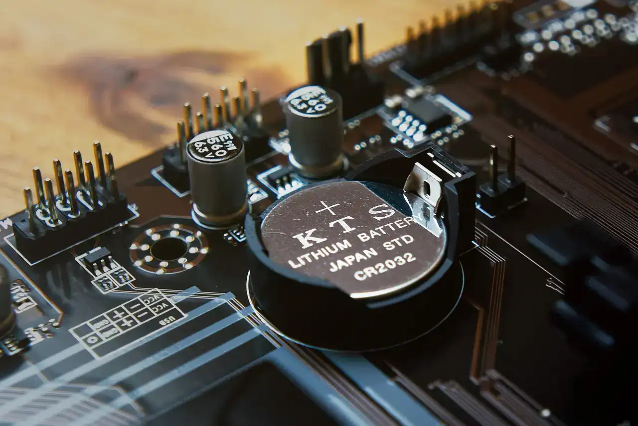 A CR2032 lithium coin cell battery in its holder on a circuit board