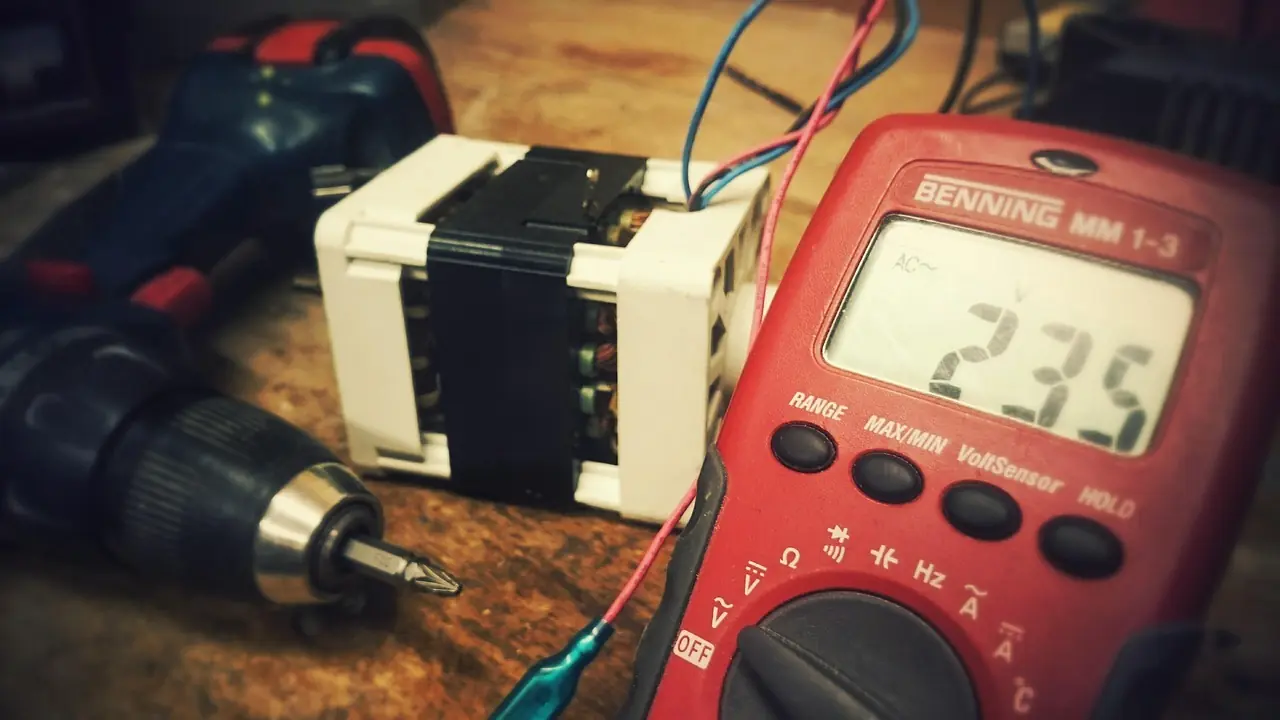 Digital multimeter with red and black test leads showing a voltage reading on a workbench