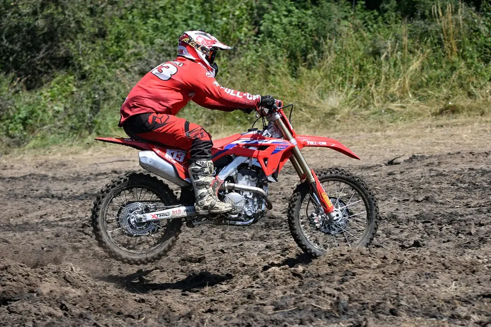 Motocross rider in full protective gear on a muddy track (a race bike, not a TT-R125)