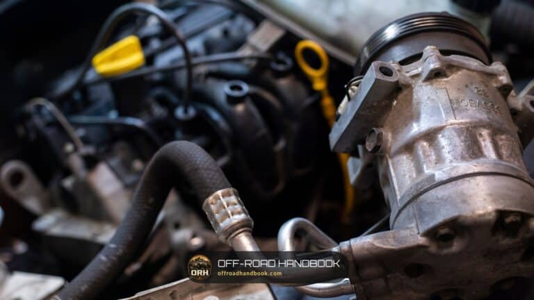 Close-up of a car engine bay with hoses and the yellow oil dipstick handle — Off-Road Handbook