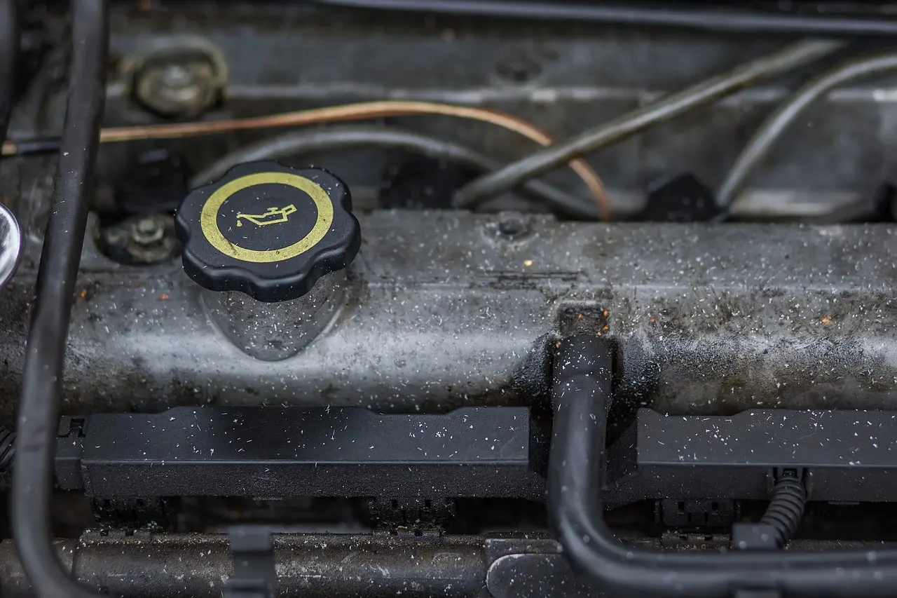 Engine oil filler cap with the oil can symbol on a dusty valve cover