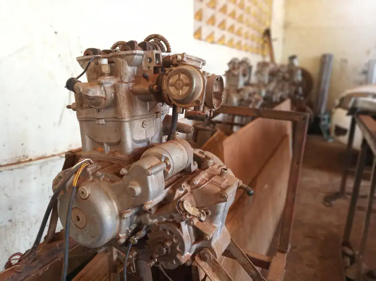 A removed car engine sitting on an engine stand in a workshop, an example of the replacement engine a shop installs