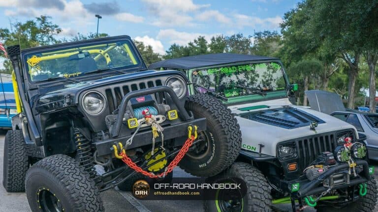 Two lifted Jeep Wranglers with winch bumpers and large all-terrain tires parked together