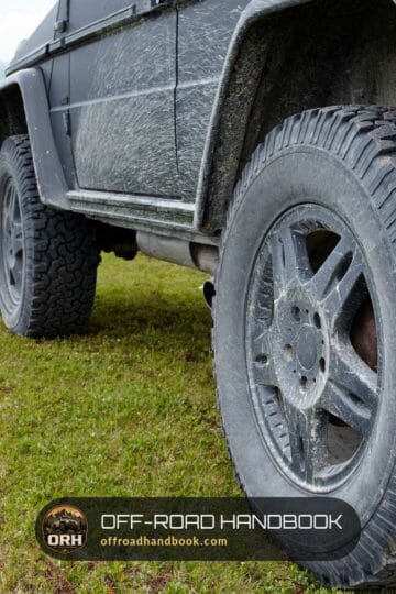 Lifted gray 4x4 SUV with mud on its all-terrain tires parked on a grassy mountain meadow — Off-Road Handbook