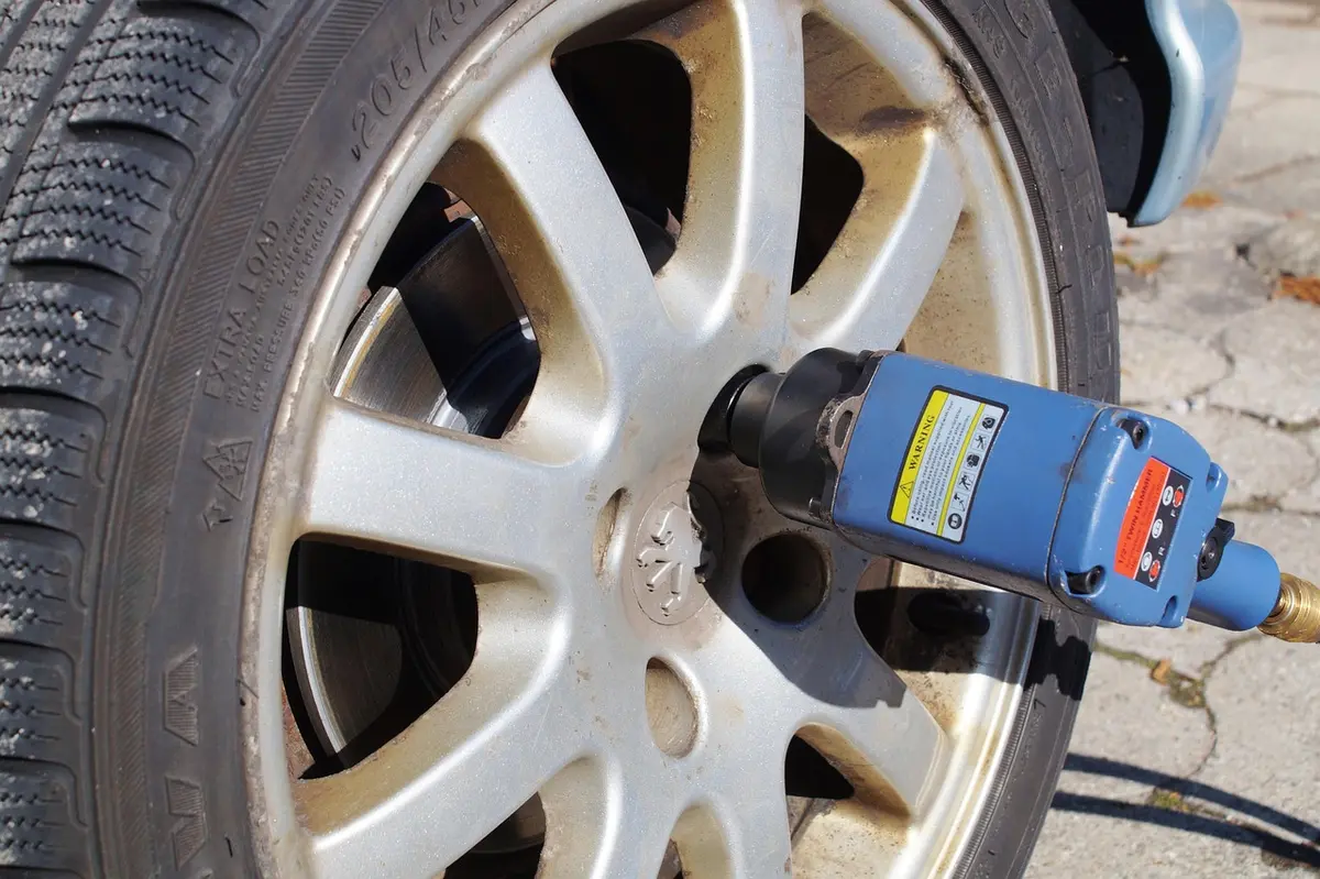 Blue air impact wrench on the lug nuts of an alloy wheel during a tire change
