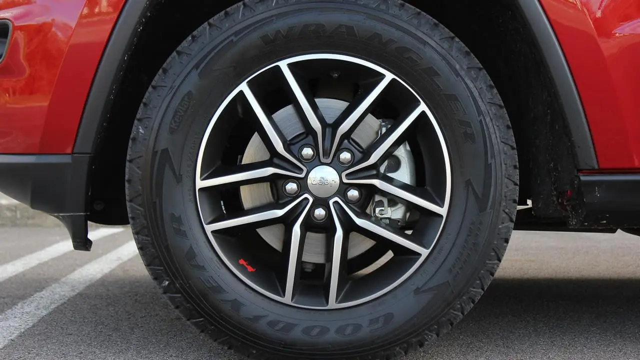 Five-lug alloy wheel on a red Jeep Grand Cherokee showing the 5x5 inch bolt circle