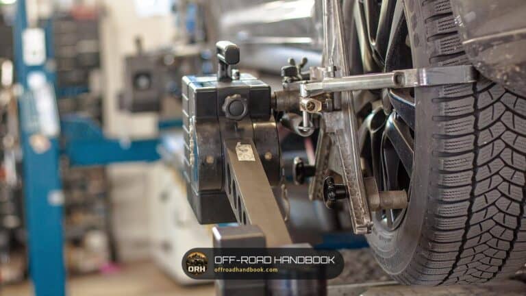 Wheel alignment sensor clamped to a car wheel in a workshop, the check that follows steering and suspension repairs