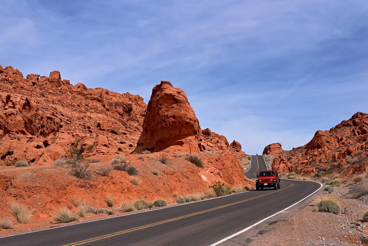 Red SUV on a winding desert road between red rock formations