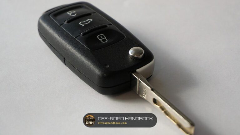 Black flip-style car key with remote buttons and a metal key blade on a gray surface