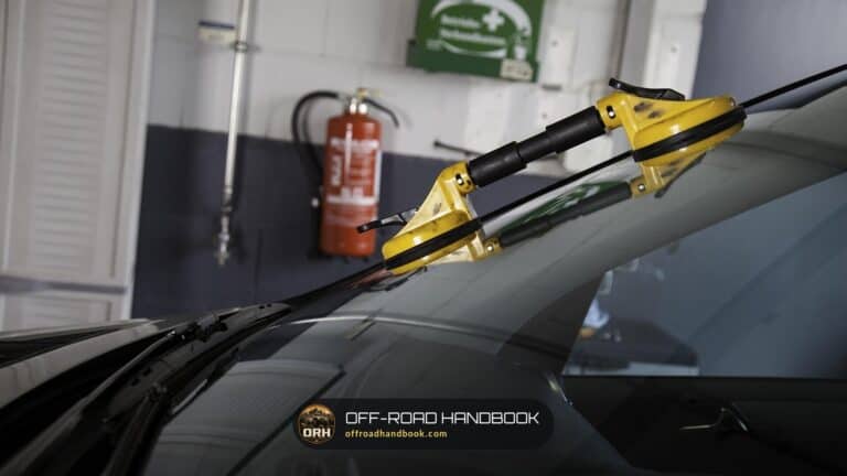 Installer's yellow suction-cup lifters on a car windshield in a glass shop