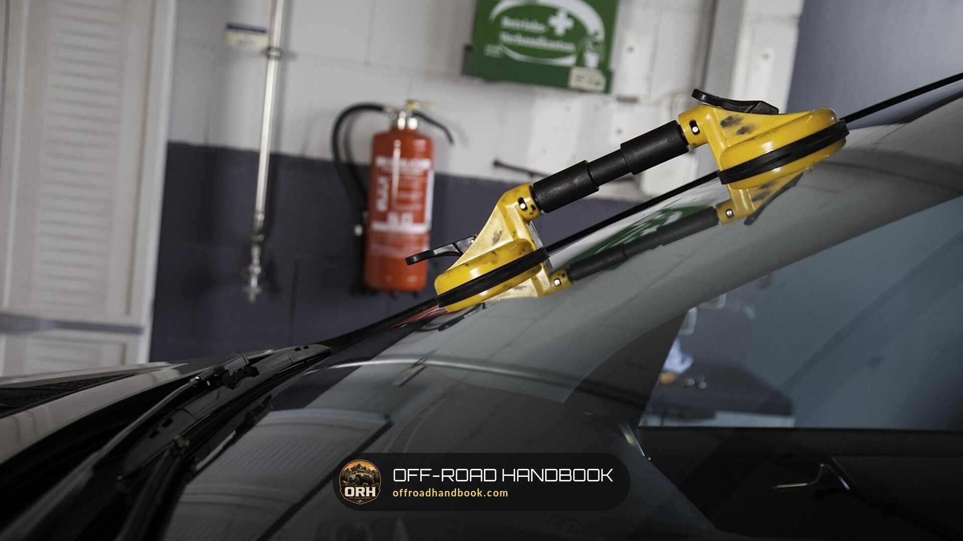 Installer's yellow suction-cup lifters on a car windshield in a glass shop