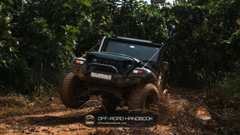 Black off-road Jeep climbing a muddy forest trail