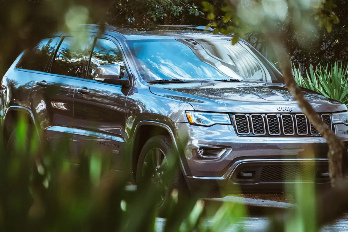 Gray Jeep Grand Cherokee SUV parked beside green plants