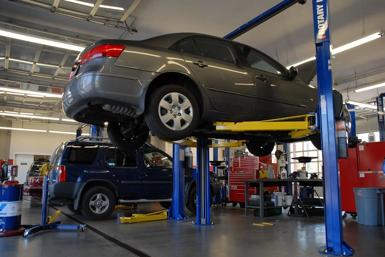 Gray sedan raised on a two-post lift in a car service bay