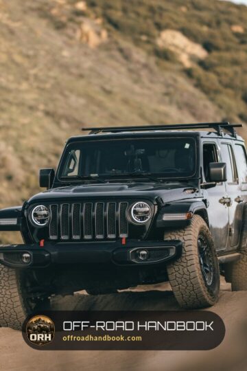 Black Jeep Wrangler driving up a dirt trail on a dry hillside