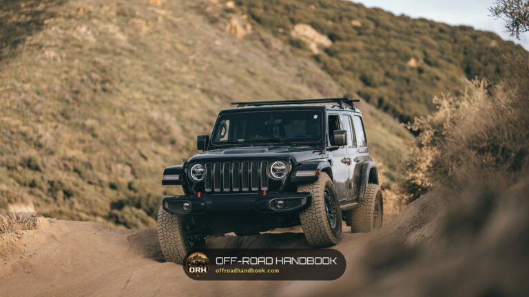 Black Jeep Wrangler driving up a dirt trail on a dry hillside