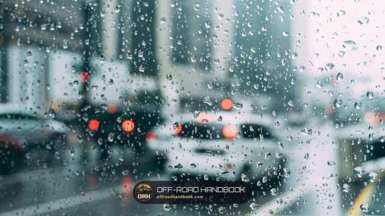 Raindrops on a wet car window with blurred cars and red brake lights behind it