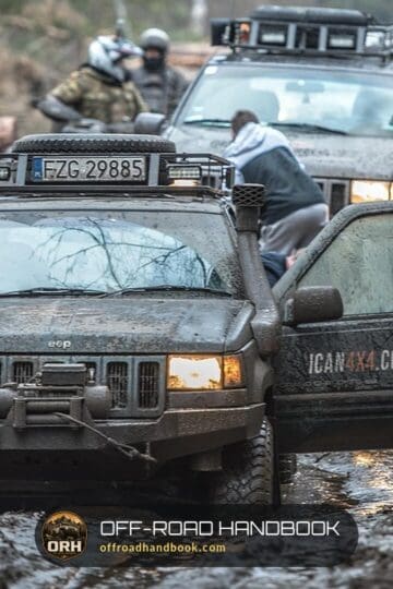 Mud-covered Jeep Grand Cherokee with a front winch on a muddy forest trail, other 4x4s waiting behind it
