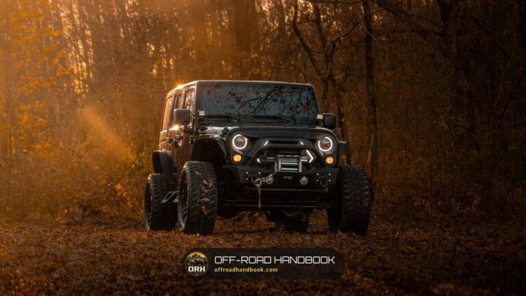 Black Jeep Wrangler with a winch bumper on a forest trail at dusk