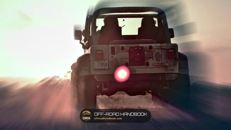 Jeep Wrangler seen from behind on a dirt road at sunrise with motion blur