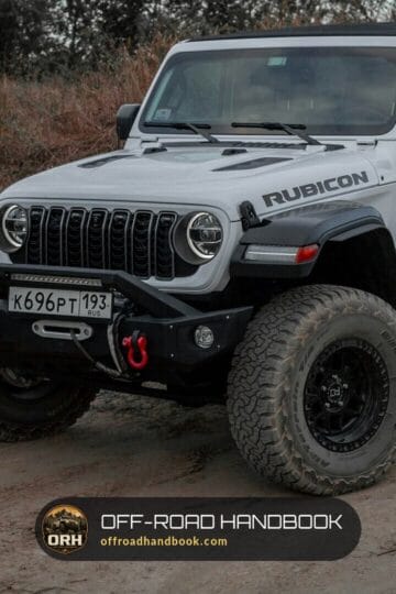 White four-door Jeep Wrangler Rubicon on large all-terrain tires parked on a dirt road