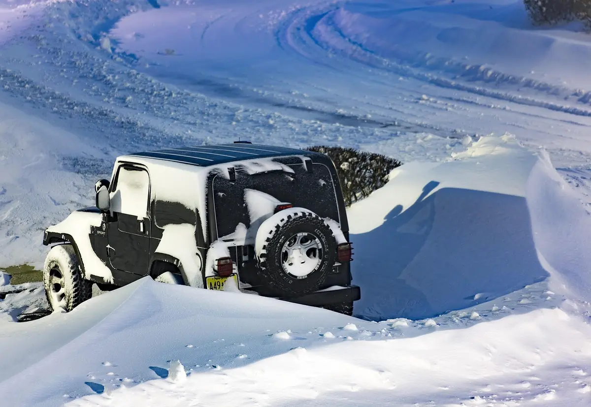 Two-door Jeep Wrangler parked in deep snow next to a plowed snowbank