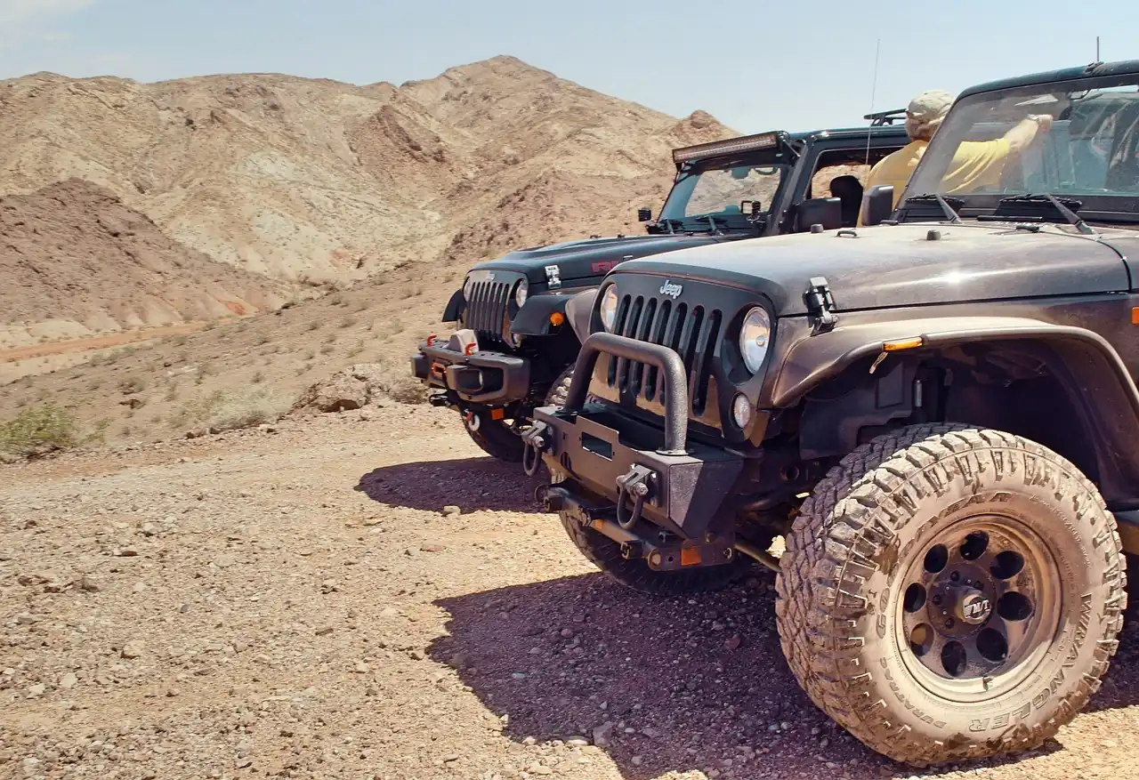 Two Jeep Wranglers parked on a rocky desert trail