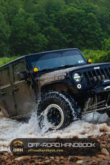 Black Jeep splashing through a shallow rocky river
